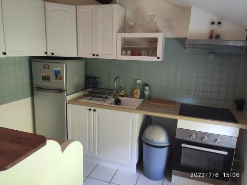 une petite cuisine avec des armoires blanches et un évier dans l'établissement Le mas, à Arles