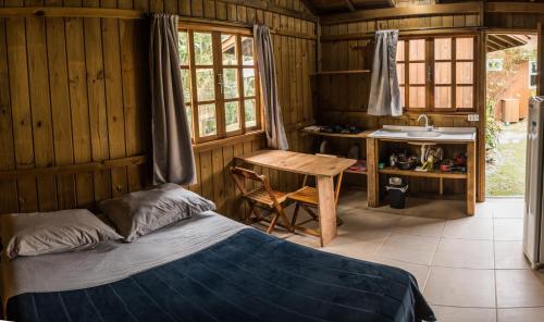 Schlafzimmer mit einem Bett, einem Tisch und einem Waschbecken in der Unterkunft Villa Rosa Cabanas in Guarda do Embaú