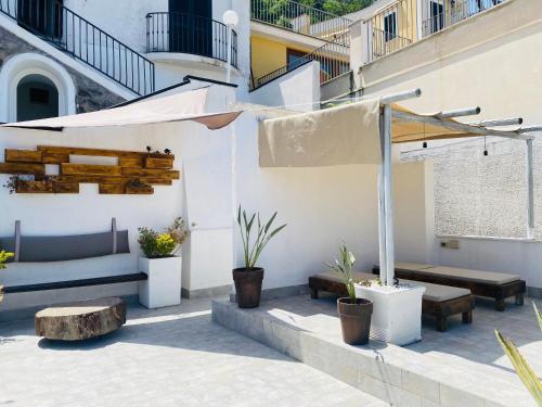 a patio with a table and benches and an umbrella at Black Market Hotel in Ischia