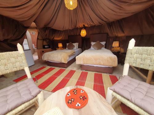 a bedroom with two beds and a table and chairs at Kasbah Africa - High Atlas Dark Sky & Nature Lodge in Ouirgane