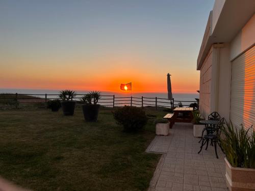 a sunset over the ocean with a lighthouse in the distance at Silver Coast Vacation - Your Unique Inn in Lourinhã