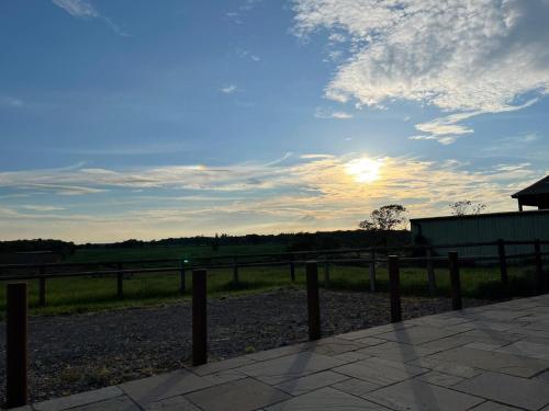 a sunset over a fence with the sun in the sky at Parkfields Barns Self Catering Accommodation in Buckingham