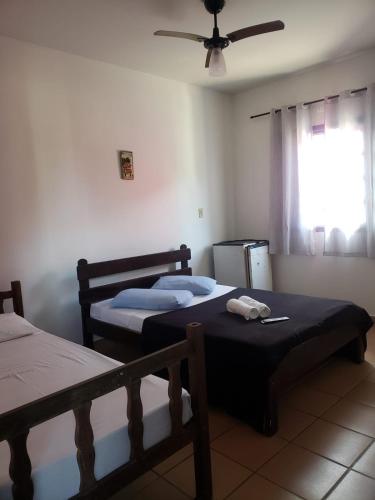 two beds in a room with a ceiling fan at Hotel Nevada Ubatuba in Ubatuba