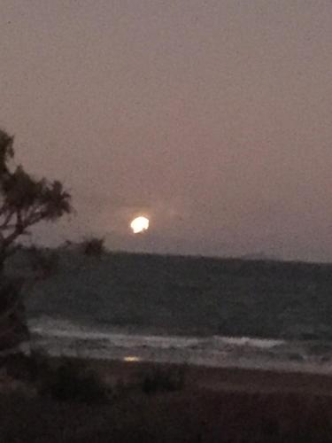 a sunset over the ocean with the moon in the sky at Sandy toes in Yeppoon
