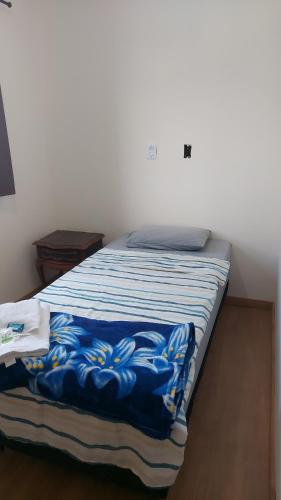 a bed with a blue and white blanket on it at Star Hotel 205 Apenas diferente in Juiz de Fora