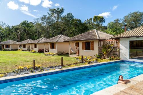 a woman sitting in a swimming pool in front of a house at Montanhas Do Visconde in Visconde De Maua
