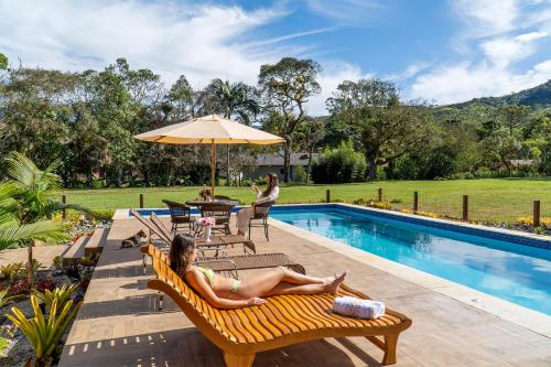 a woman laying on a bench next to a swimming pool at Montanhas Do Visconde in Visconde De Maua