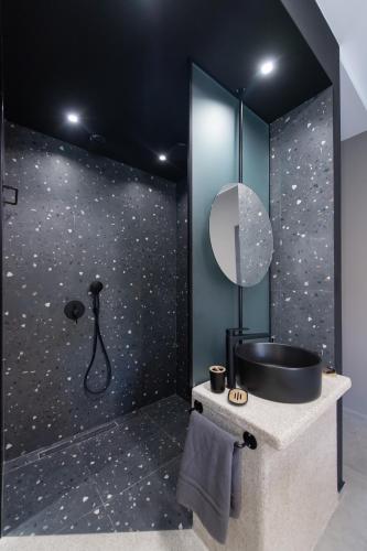a bathroom with a black wall with a shower and a sink at COCO SUITES in Vasiliki