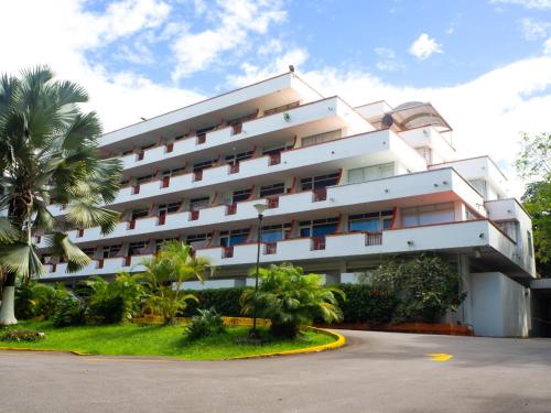 a large white building with palm trees in front of it at Hotel del Llano in Villavicencio
