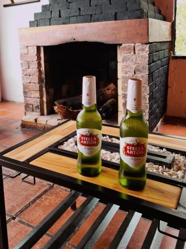 dos botellas de cerveza sentadas en una mesa frente a una chimenea en Hostal San Rafael La Calera, en La Calera