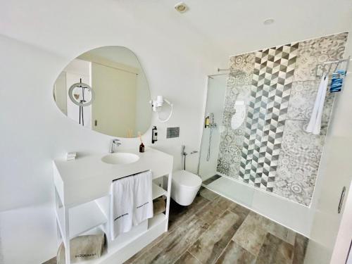een witte badkamer met een wastafel en een douche bij DESIGN SUITES Boutique Hotel - Adults Only in Santa Maria