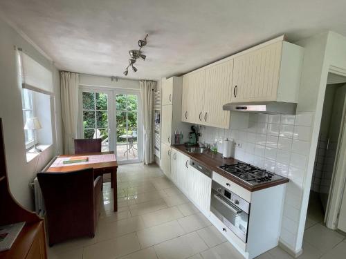 a kitchen with white cabinets and a stove top oven at Cosy holiday home overlooking the meadows in Spijk