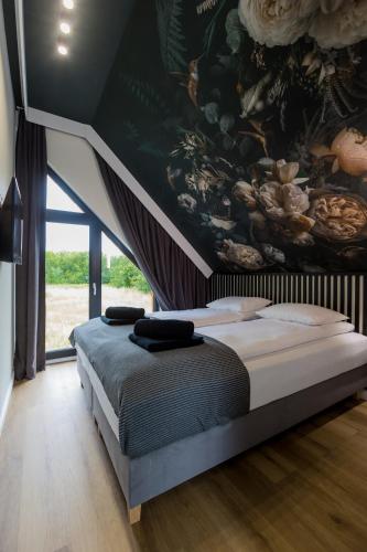 a bedroom with a large bed with a painting on the wall at Mare Boutique Houses in Niechorze