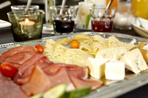 Una bandeja de comida con queso y carnes en una mesa. en Kühne's 4 Sterne Komfort-Apartments, en Braunlage