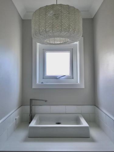 a white bathroom with a sink and a window at The Great Escape, Luxury Waterfront, HotTub in Whitianga