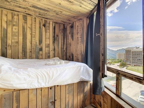 Cette chambre en bois comprend un lit et une grande fenêtre. dans l'établissement Bel Appart Rénové · 6 Pers · Pied des Pistes · Balcon · 2 Flocons Bronze - FR-1-344-776, aux Menuires