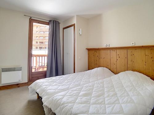 a bedroom with a large white bed and a window at Appartement Les Menuires, 4 pièces, 8 personnes - FR-1-344-799 in Levassaix