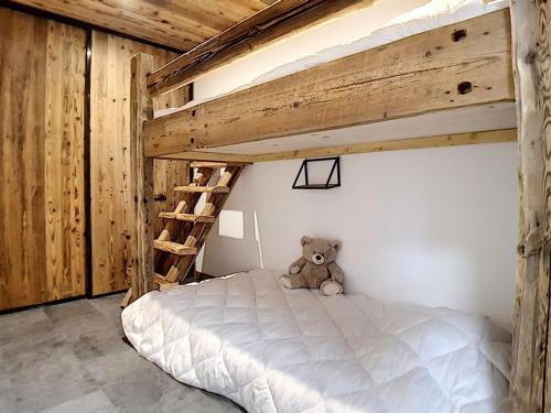 a teddy bear sitting on a bed in a bedroom at Appartement Les Menuires, 2 pièces, 6 personnes - FR-1-344-831 in Levassaix