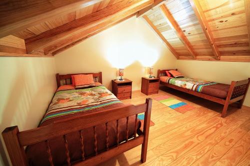 a attic bedroom with two beds and wooden ceilings at Herdade do Pedregal in Ponta do Pargo