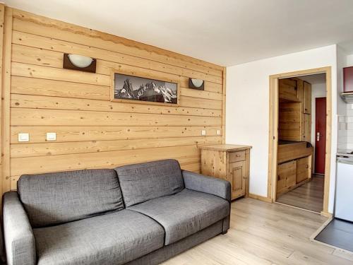 - un salon avec un canapé et un mur en bois dans l'établissement Studio rénové au centre avec balcon - FR-1-344-926, aux Menuires