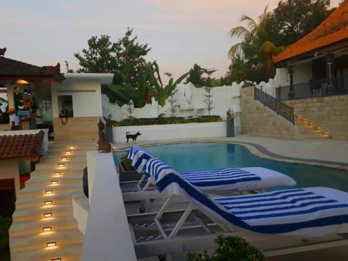 a swimming pool with two lounge chairs next to a house at Soul Lodge Villa Lovina in Banjar
