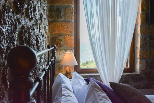 a bedroom with a bed with a lamp and a window at Nymfes Guesthouse in Synikia Mesi Trikalon