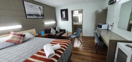 a hotel room with a bed and a desk and a kitchen at Morwell Parkside Motel in Morwell