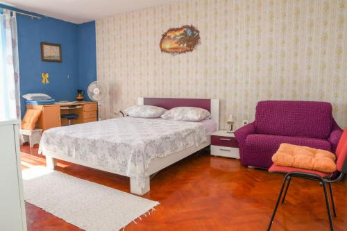 a bedroom with a bed and a purple chair at Central sea view apartment in Komiža