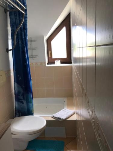 a bathroom with a toilet and a tub and a window at Apartmán Juli in Tatranská Lomnica