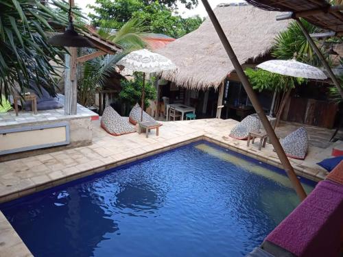 a swimming pool with chairs and umbrellas next to a house at La Boheme Mini in Gili Trawangan