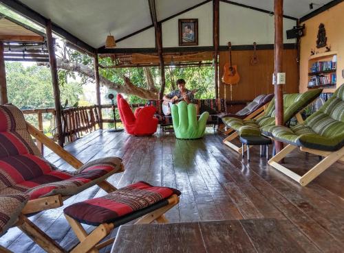 a man sitting in a living room with chairs at Tree House Bungalows Koh Tao in Koh Tao