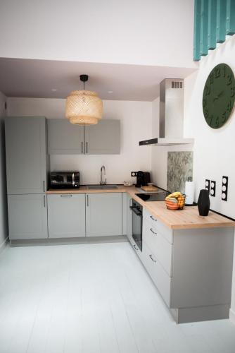 une cuisine avec des placards blancs et une horloge murale dans l'établissement maison MARTEL nimes centre climatisé, à Nîmes