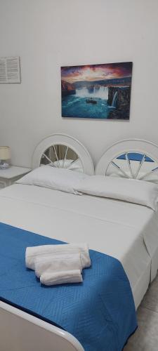 a large white bed with a blue blanket on it at Villa da Rosa in Olbia