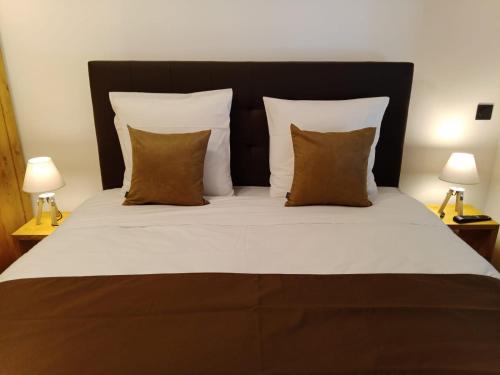 a large bed with white sheets and brown pillows at Gîtes de l'Orée du Bois - Boussières in Boussières