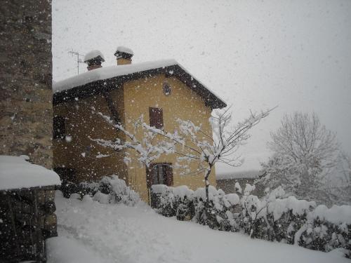 a house covered in snow in a yard at B&B Casabasoti in Valli del Pasubio