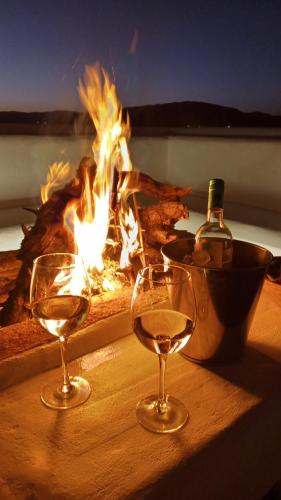 two glasses of wine sitting on a table in front of a fire at I Víla in Villa Carlos Paz