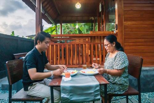 mężczyzna i kobieta siedzący przy stole jedzący jedzenie w obiekcie Pondok Biu w mieście Denpasar