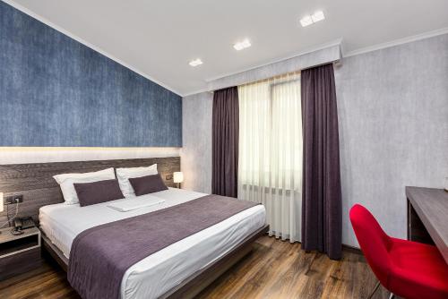 a hotel room with a bed and a red chair at Kope Palace in Tbilisi City