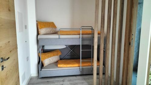 a room with three bunk beds with orange pillows at Agritur La Fenice in Brez