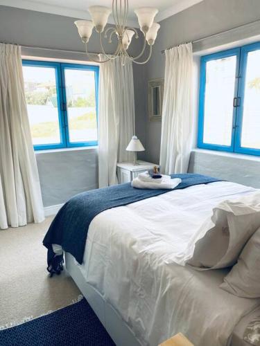 a bedroom with a large white bed with two windows at Casa Balena - Gansbaai seafront accommodation, back-up power in Gansbaai