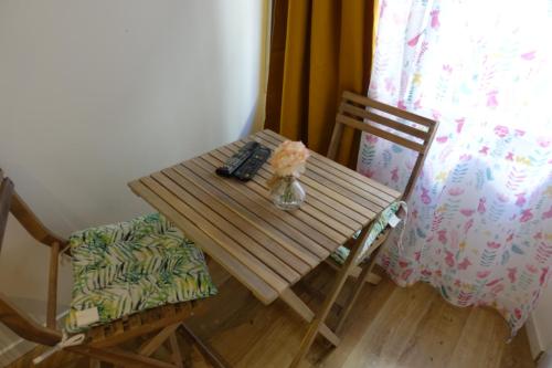 une table en bois avec un vase de fleurs et une chaise dans l'établissement Studio 07 Argeles sur Mer . La plage à pied, L'Espagne à 30 mn, à Argelès-sur-Mer
