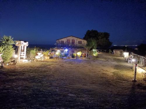 a house with lights in a field at night at Casolare La Torre in Scopello