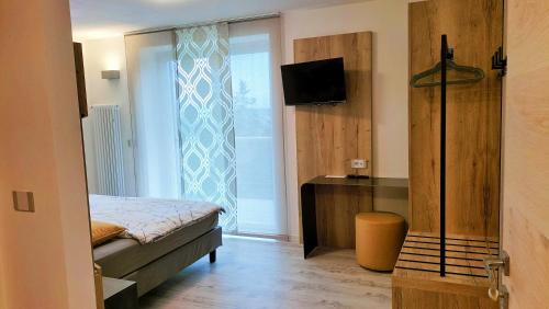 a bedroom with a bed and a television and a window at Agritur La Fenice in Brez