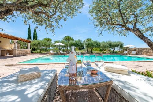 - une table avec des verres à vin à côté de la piscine dans l'établissement Maison d'Hôtes Les Caroubiers, à Montségur-sur-Lauzon