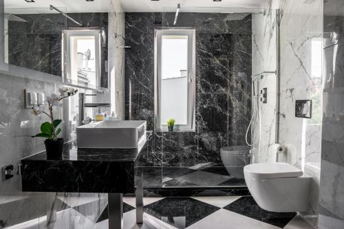 Baño en blanco y negro con lavabo y aseo en Strand Palazzo, en Sopot