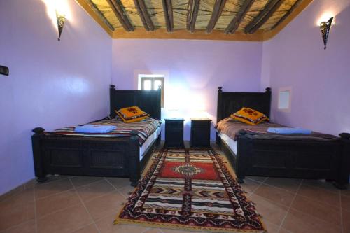 two beds in a room with purple walls at Tizourgane Kasbah in Tiguissas