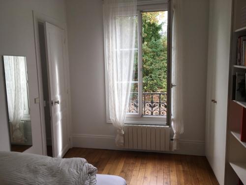 una camera da letto con finestra e pavimento in legno di Alex Flats a Parigi