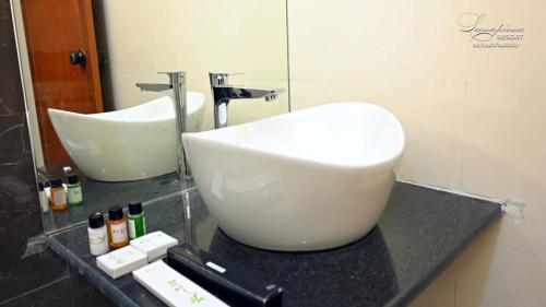 a bathroom with a large white sink and a mirror at LUNAPIENA RESORTS in Tiruvankod