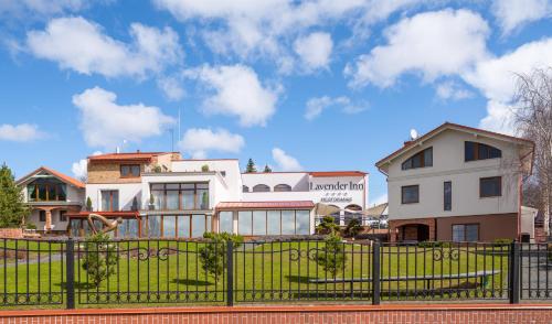 a white house with a fence in front of it at Lavender Inn Guest House in Viešvėnai