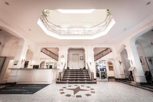 ein großes weißes Gebäude mit einer Treppe und einer Decke in der Unterkunft Strandhotel Kurhaus Juist in Juist